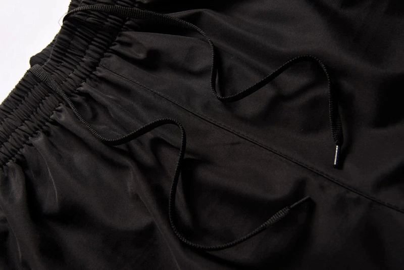 Close-up of black tracksuit pants with elastic waist and drawstrings for a snug fit.